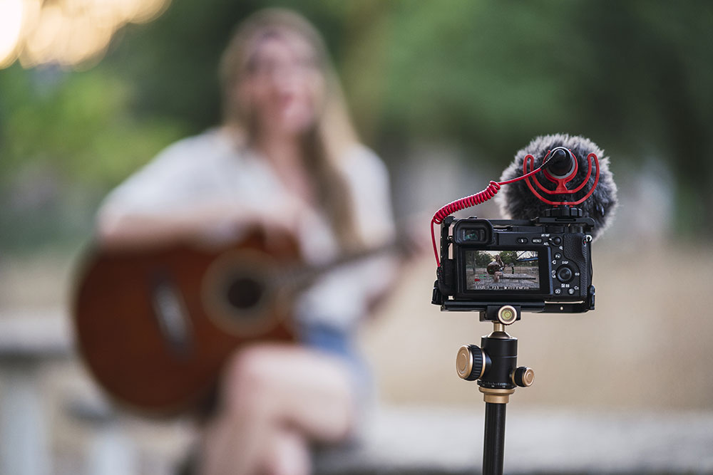 adult-woman-playing-acoustic-guitar-park-recording-herself